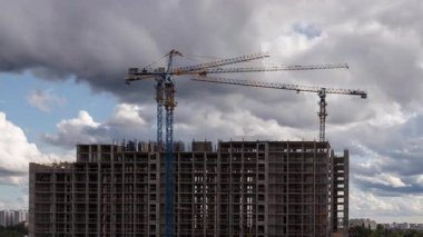 Konut inşaatı üzerinde çalışan vinçlerin yakın görüntüsü, statik çekim ilerlemesi, emlak yatırım bağlamı ve kentsel gayrimenkul geliştirme