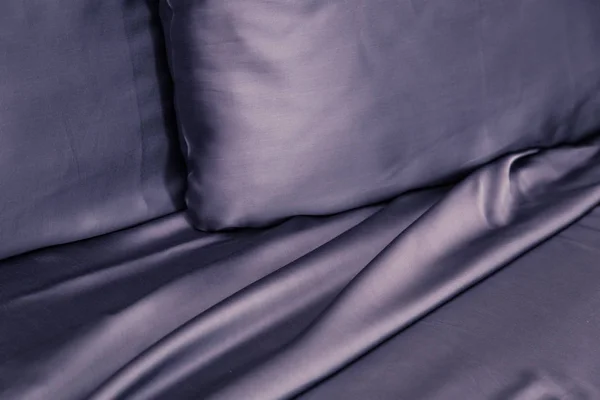 Beautiful dark bedding on the bed with expensive silk, pillows and sheet closeup