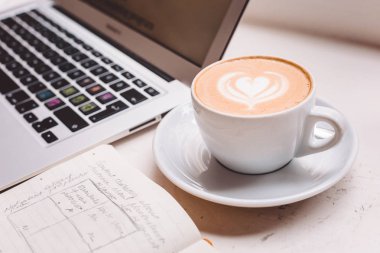 Dizüstü bilgisayar ile bir grafik, zamanlama, bir bardak kahve ile kalp süsleme ve defterini notlar, iş iş ve verimlilik için yer ile