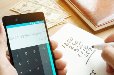 Ev bütçe hesaplanması için akıllı telefon kullanan adam. Para sayma.