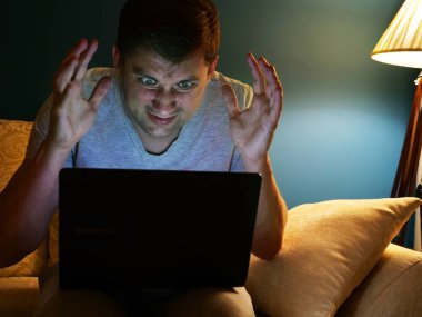 Kızgın adam evin içinde laptop bilgileri okuma.