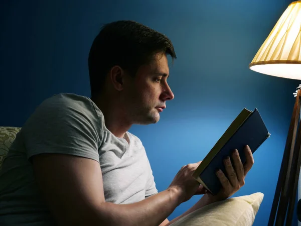 Мужчина Диване Читает Книгу Вечером — стоковое фото