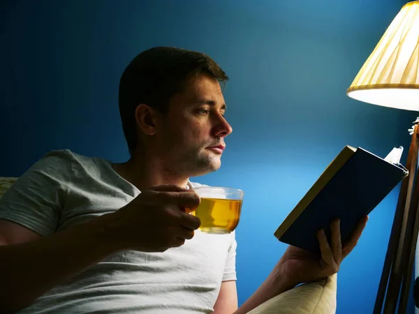 Homem Com Xícara Chá Está Lendo Livro Noite Relaxamento — Fotografia de Stock