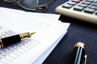 Defter tutma. Bir masa üzerine rakamlar ve hesap makinesi ile mali rapor.