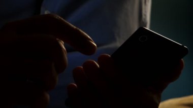 Adam akıllı telefon evde sosyal medyada haber okumak için kullanıyor. Akşam. 