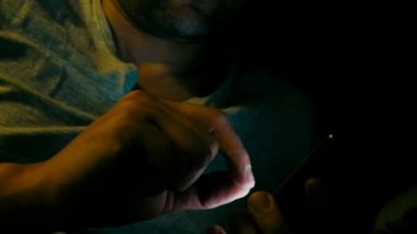 Adam gece smartphone içinde sosyal medya okuma.