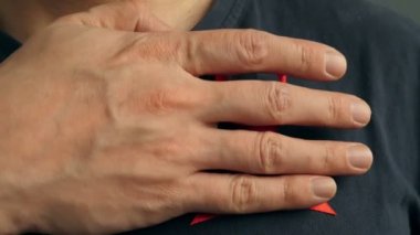 Bir adam bir kırmızı farkındalık şerit gömleğini için ekler. HIV AIDS kavramı.