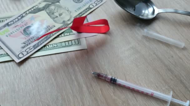 hiv / aids-Konzept. Ein rotes Band fällt auf einen Tisch mit einer Spritze mit Medikamenten. Betäubungsmittelsucht.