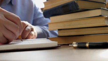 Adam Not defteri ve yığın kitaplığındaki kitap yazıyor. Eğitim ve bilgi kavramı.