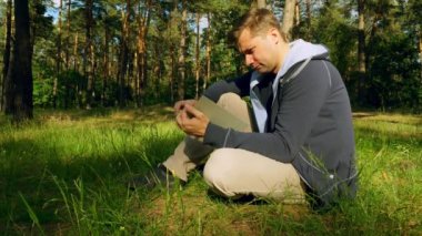 Adam açar ve parkta çimlere oturup kitap okur.