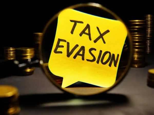 Magnifying glass and words tax evasion with money.