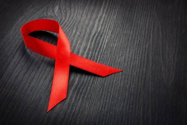 Karanlık bir masa üzerine kırmızı farkındalık şerit. HIV AIDS kavramı.