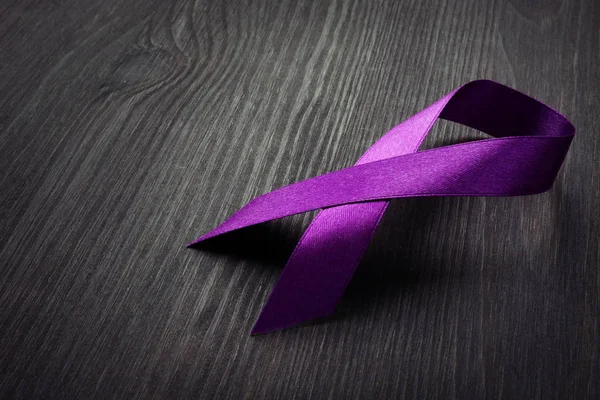 Purple awareness ribbon on a desk. Pancreatic cancer.