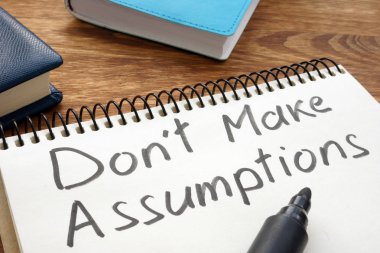 Don't Make Assumptions. Notepad with marker on a table. clipart