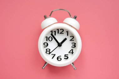 Pembe bir yüzey üzerinde beyaz alarm saati.