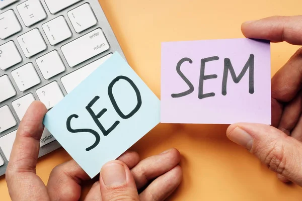 Hands holding cards with SEO and SEM. — Stock Photo, Image