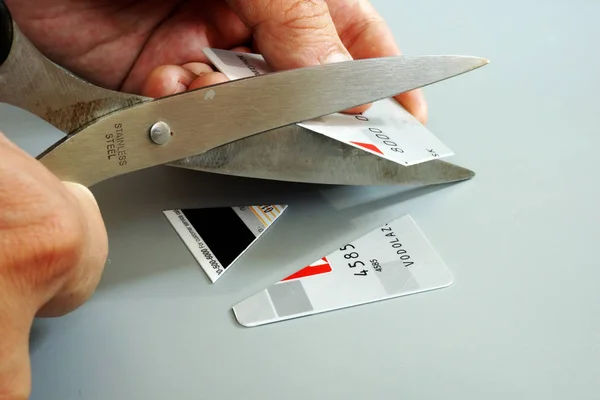 Raus aus den Kreditkartenschulden. Mann schneidet Bankkarte ab. — Stockfoto