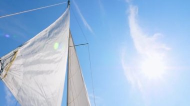 Yatın beyaz yelkenleri ve bulutlu mavi gökyüzü.