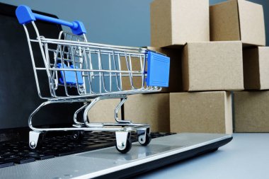 E-ticaret ve online alışveriş konsepti. Bir dizüstü bilgisayarda kutular ve alışveriş kartı.