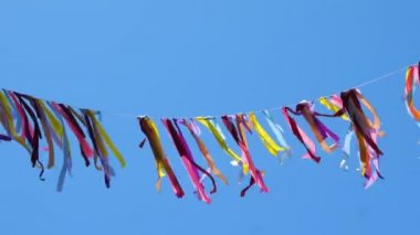 Mavi gökyüzünde ve yaz rüzgarında çırpınan renkli kurdeleler.