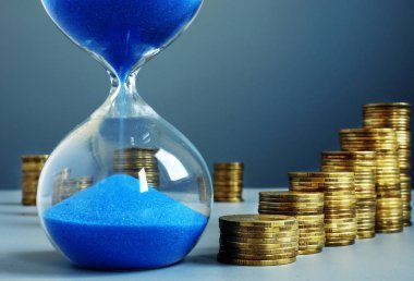 Zaman ve para. Tasarruf olarak kum saati ve sikke yığını.