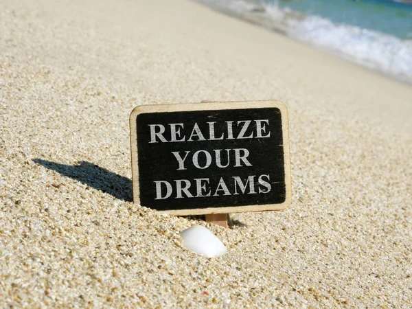 Realize your dreams written on a wooden plate.