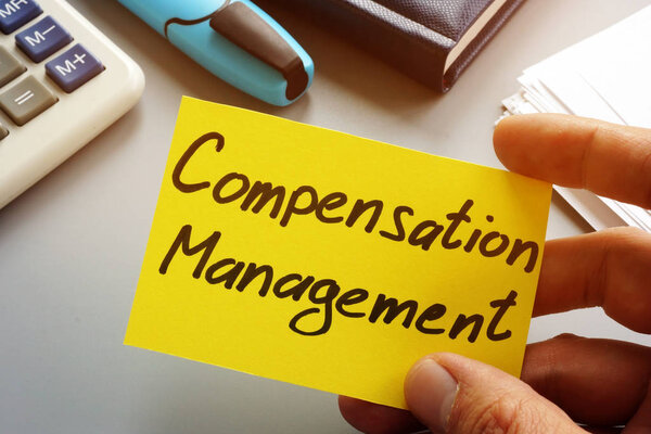 Compensation Management sign on a memo stick in hand.