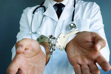 Tıbbi yanlış tedavi konsepti. Elleri kelepçeli doktor.
