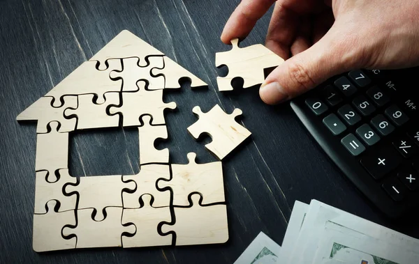 Savings on the purchase of real estate or a mortgage. A hand is collect a house from pieces of a puzzle. — Stock Photo, Image