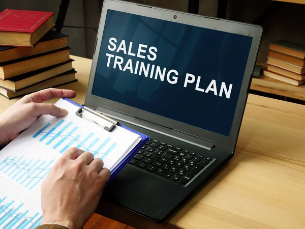 Manager reads Sales Training Plan in the laptop.