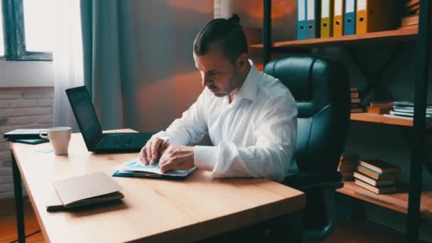 La cámara se mueve alrededor de la mesa con un hombre de negocios sentado revisando los informes financieros . — Vídeo de stock