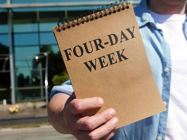 El hombre propone un signo semanal de cuatro días. Bloc de notas en mano. — Foto de Stock