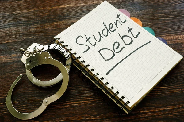 Student debt handwritten sign in the notebook and handcuffs.