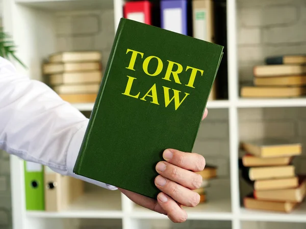 Mano mostra un libro di legge Tort in ufficio. — Foto Stock