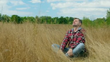 Günlük giysiler içindeki bir adam doğada meditasyon yapar, dinlenir ve çimlere düşer..