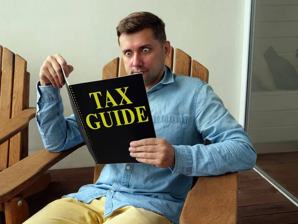 税金ガイドの概念。椅子に座っている男が本を読む. — ストック写真