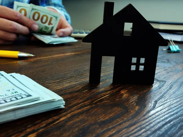 El hombre está contando efectivo para comprar una casa, hipoteca, o alquiler. —  Fotos de Stock