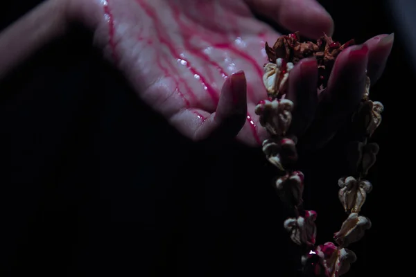 Die Blutende Hand Fängt Die Getrocknete Blumengirlande Auf Schwarzem Hintergrund — Stockfoto