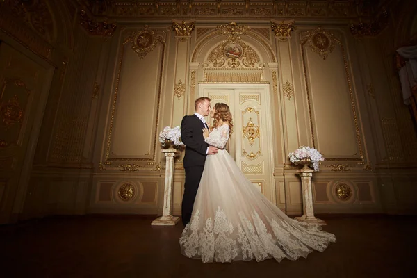 Encantadora pareja de boda en el interior en estilo barroco se abraza en el gran palacio real — Foto de Stock