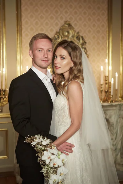 Couple de mariage dans un intérieur luxueux dans le style baroque se serre dans ses bras. Belle fille modèle en robe blanche. Un homme en costume. Mariée beauté avec marié. Portrait féminin et masculin. Femme avec dentelle — Photo