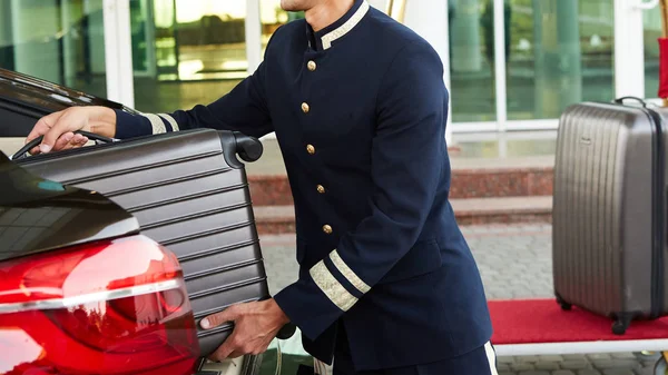 Bellboy prendere il bagaglio di ospite da te auto per la sua camera — Foto Stock