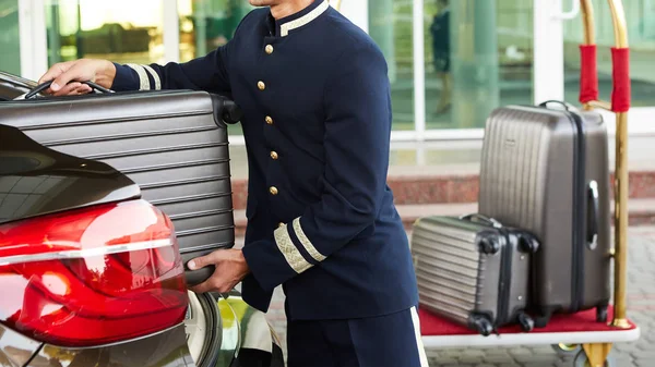 Hotelangestellter bringt Gepäck von Gast aus Auto auf sein Zimmer — Stockfoto