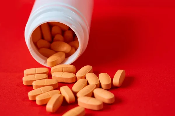 Pills spilling out of pill bottle on red. Top view with copy space. — Stock Photo, Image