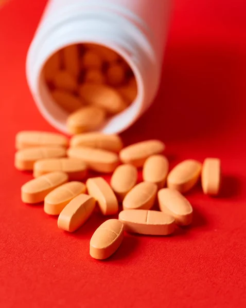 Pills spilling out of pill bottle on red. Top view with copy space. — Stock Photo, Image