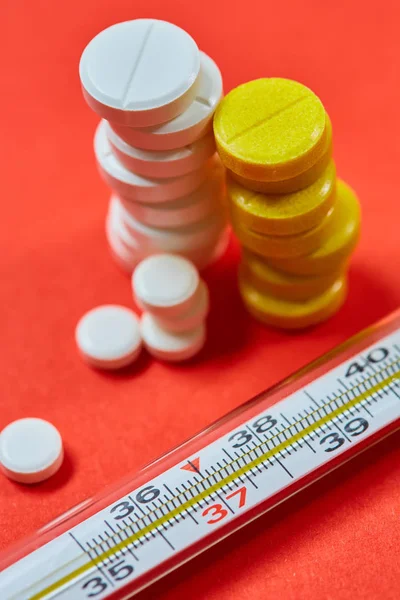Termometro a mercurio e pillole mediche sullo sfondo — Foto Stock