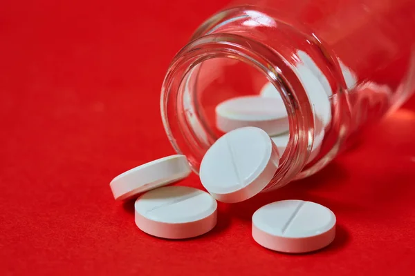 Pills spilling out of pill bottle on red. Top view with copy space. — Stock Photo, Image