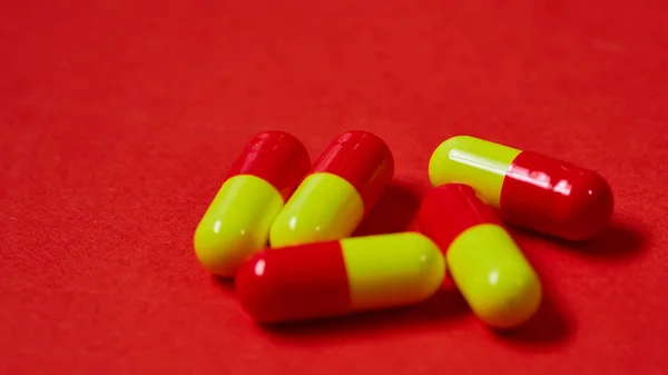 Pillen, die aus der Tablettenflasche auf rot verschüttet werden. Ansicht von oben mit Kopierraum. — Stockfoto