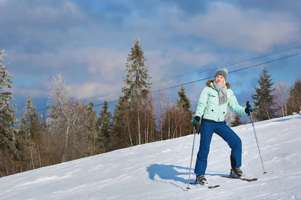 Jovem esquiador bonito monta uma estância de esqui em um fundo de céu azul — Fotografia de Stock