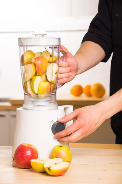 Young man cooking apple smoothie in blender — Stock Photo, Image