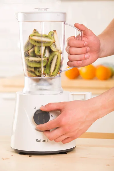 Young man cooking kiwi smoothie in blender — Stock Photo, Image